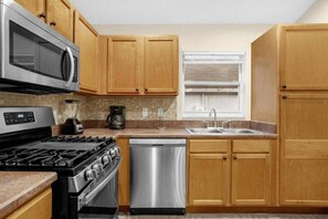 A kitchen with wooden cabinets, a stainless steel microwave, a stove, a dishwasher, and a window with blinds. - Private Pool, 4 Miles to Disney-6BR / 4 baths Home (Kissimmee)