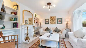 A living room with white furniture, a fireplace, decorative items, and framed artwork on the walls.