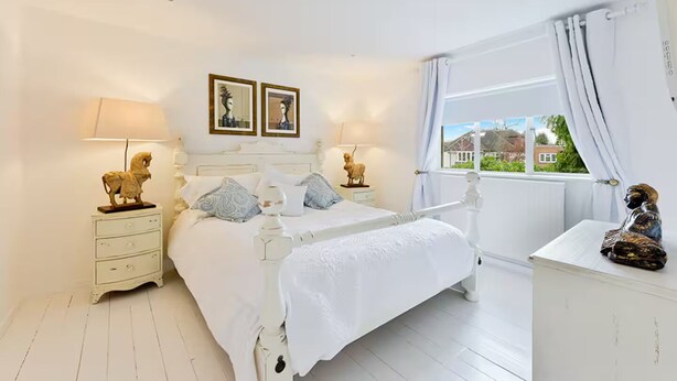 A bedroom with a bed, bedside tables, a dresser, and a window with curtains.