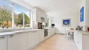 A modern kitchen with white cabinetry, a built-in oven, and a large window offering a view of the outdoors.