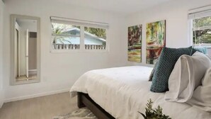 Une chambre à coucher avec un lit, deux fenêtres et une porte.