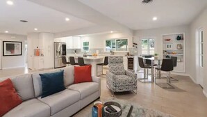 Un salon moderne avec un canapé, un fauteuil à motifs et un coin repas comprenant une table et des chaises.