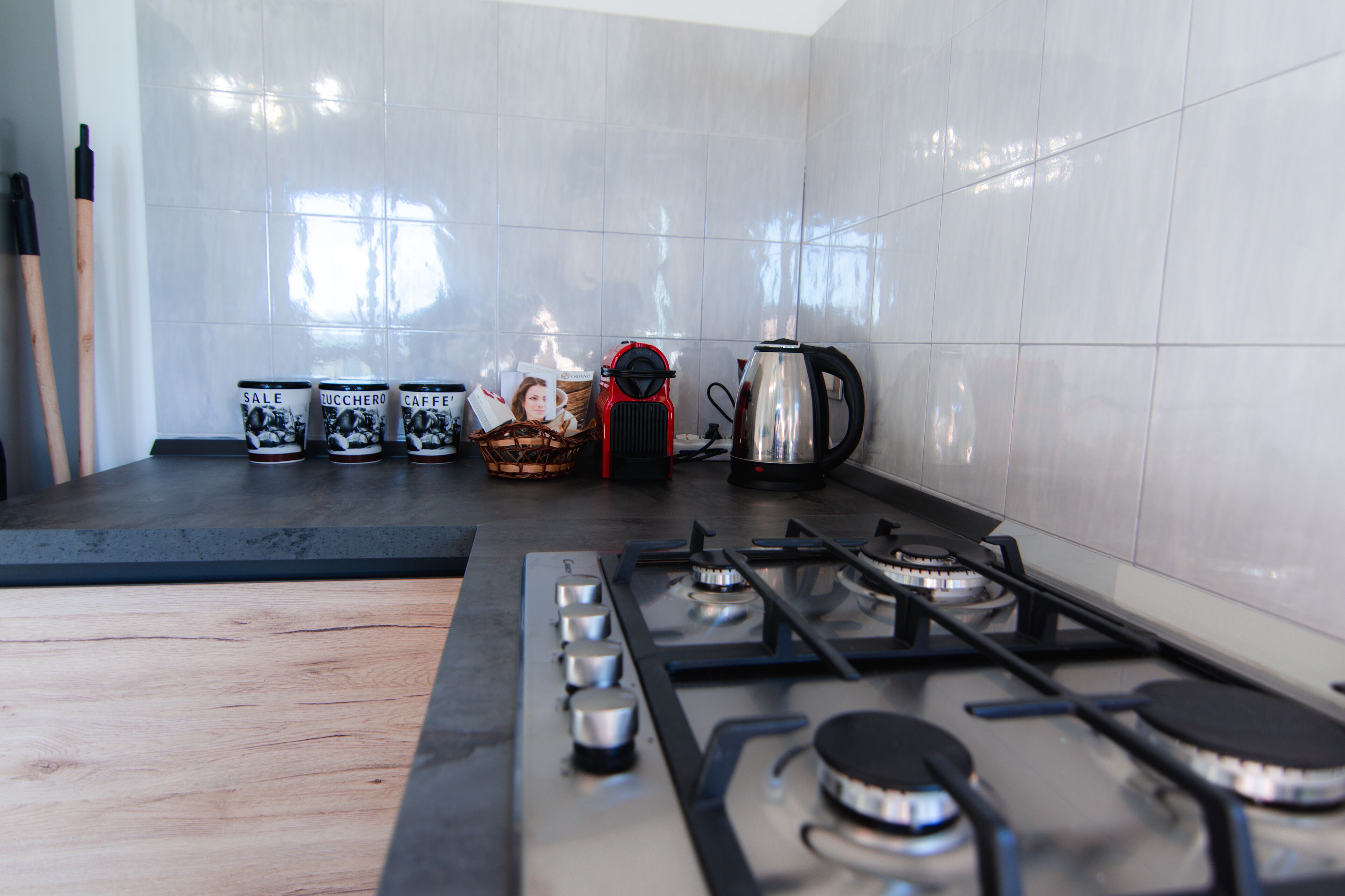 A kitchen with a gas stove, a coffee maker, and several mugs on the counter.