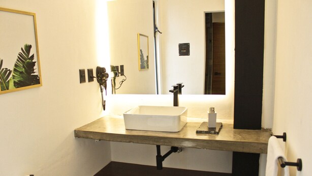 A bathroom with a white sink, a mirror, a towel rack, and a toilet paper holder. - JR lofts (San Luis Potosi)