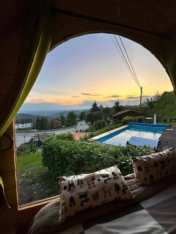 Ein Zimmer mit einem großen Bogenfenster mit Blick auf einen Swimmingpool und eine Straße.