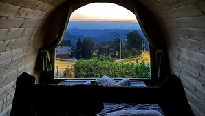 A cozy room with a wooden ceiling and a large arched window. A bed with a white mattress and a blanket is visible, and a pillow is placed on it. - B&B La Tana dello Scoiattolo - Adults Only (Murazzano)