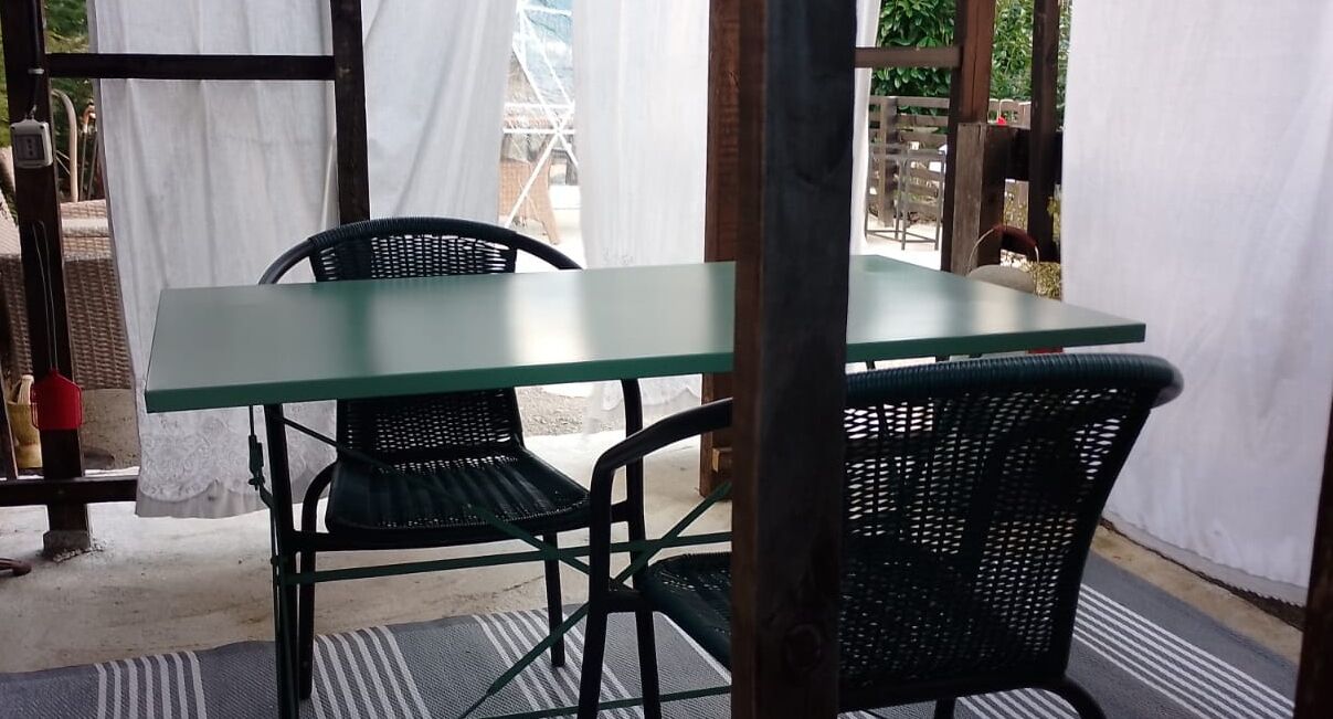 A covered outdoor seating area with a table and two chairs.