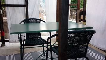 A covered outdoor seating area with a table and two chairs.