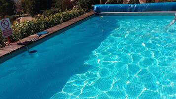 Una piscina con agua azul cristalina, rodeada por una terraza de madera y un cartel que indica prohibido bucear.