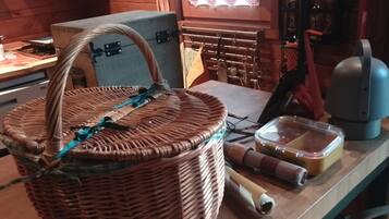Un panier en osier avec une anse, posé sur une table en bois, un récipient en plastique et un appareil électroménager bleu.