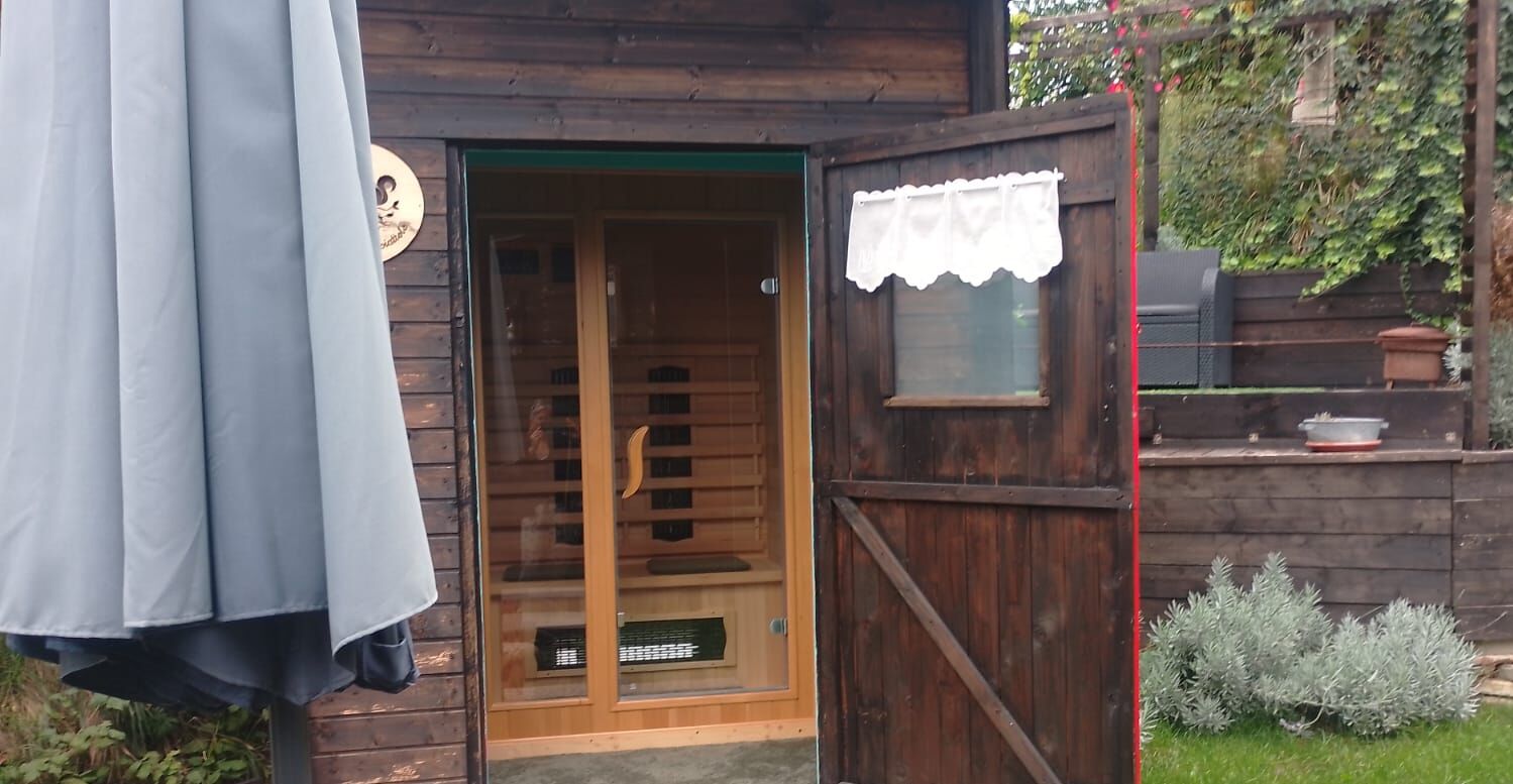 Una cabaña de madera con la puerta abierta, mostrando un cuarto con ventana y una mesita.