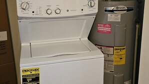 A front-loading washer and dryer unit with an ENERGYGUIDE sticker, a water heater, and a utility meter. - Cozy Lakeside Cottage near Legoland, Winter Haven! Florida vacation ready! (Winter Haven)