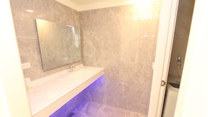 Un baño con lavamanos de mármol, espejo y zona de ducha.