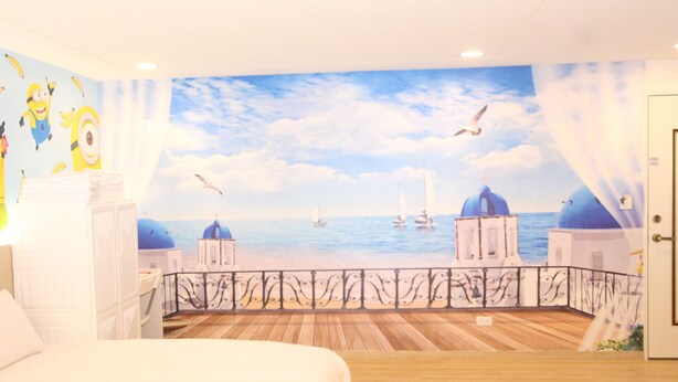 Un dormitorio con un mural de una vista al mar, una cama y piso de madera.