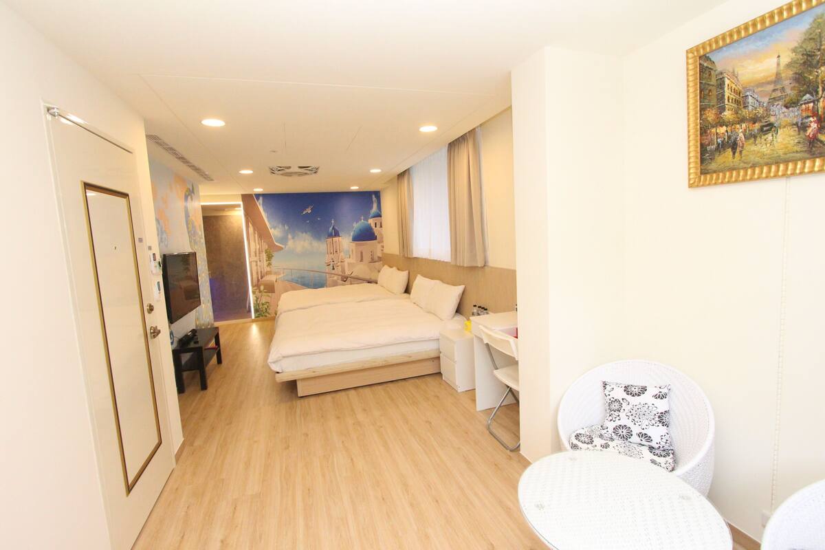 Habitación de hotel con cama, escritorio, silla y un cuadro en la pared.
