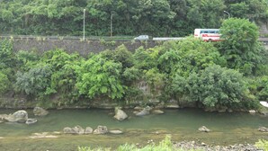 Un río con rocas y un puente con un autobús.