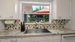 Una cocina con ventana, un lavamanos y un salpicadero de azulejos.