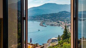 Een kuststadsgezicht met een jachthaven, bergen op de achtergrond en een uitzicht door een raam.