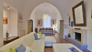 A spacious living room with a white sofa, a dining area with a table, and a fireplace. - Villa Afrodite 8, Emma Villas (Milazzo)