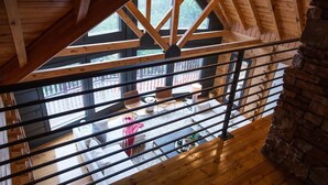 A wooden interior with a balcony overlooking a patio area. - The Ridge: A Modern Cabin (Bostic)