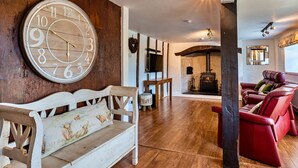 Un salon chaleureux avec un banc en bois, un canapé rouge et une grande horloge murale.