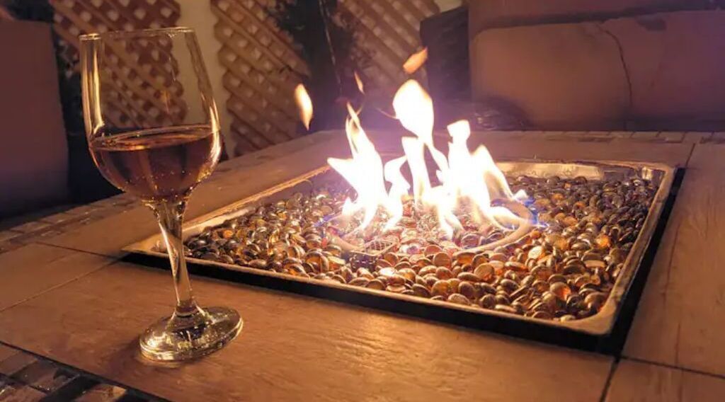 Una copa de vino sobre una bandeja junto a una chimenea hecha de piedras.