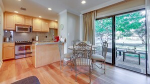 A modern kitchen with wooden cabinets, stainless steel appliances, and a dining area with a glass table and metal chairs. - Serene Napa Retreat w/ Pool Access & Patio! (Napa)
