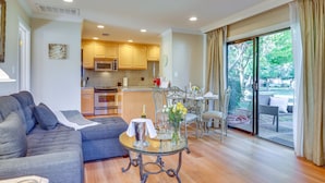 A modern living room with a grey sofa, a glass coffee table, and a dining area with a table and chairs. - Serene Napa Retreat w/ Pool Access & Patio! (Napa)