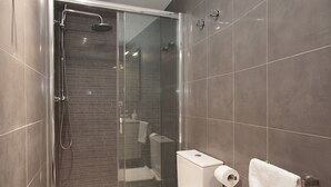 A modern bathroom with a glass-enclosed shower, a toilet, and a sink. - Alissia 1 - Habitat Apartments (Barcelona)