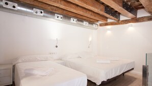 A hotel room with two beds, wooden beams, and a white wall.
