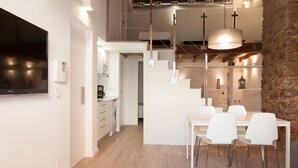A modern kitchen with white cabinets, a built-in oven, and a hanging light fixture.