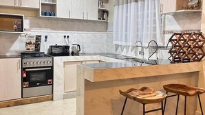 Una cocina moderna con una isla central, electrodomésticos de acero inoxidable e iluminación colgante.