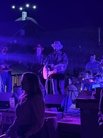 Una banda tocando en el escenario, con una batería y un teclado al fondo.