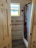 Un interior de madera con una ventana, una estantería con diversos objetos y una puerta.