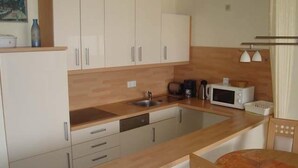 A compact kitchen with white cabinets, a wooden countertop, a sink, a microwave, and a coffee maker. - Nautilus, Ferienwohnung 23 (Cuxhaven)