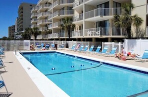 A swimming pool with lounge chairs and a white fence. - Experience Spectacular Oceanfront Views in our Cozy Condo  (North Myrtle Beach)