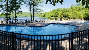 A swimming pool with a curved edge, surrounded by a metal fence, and trees in the background. - MountainwoodMemories LkHarmony 5bedroom Pool Beach SkiResort Tennis (Lake Harmony)