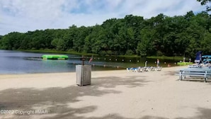 A beach with a sandy shore, a green inflatable boat, and a row of blue lounge chairs. - MountainwoodMemories LkHarmony 5bedroom Pool Beach SkiResort Tennis (Lake Harmony)