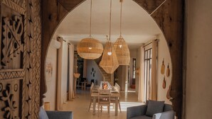 Un'ampia zona giorno con un'alta porta ad arco, un tavolo da pranzo apparecchiato per quattro persone e due divani.