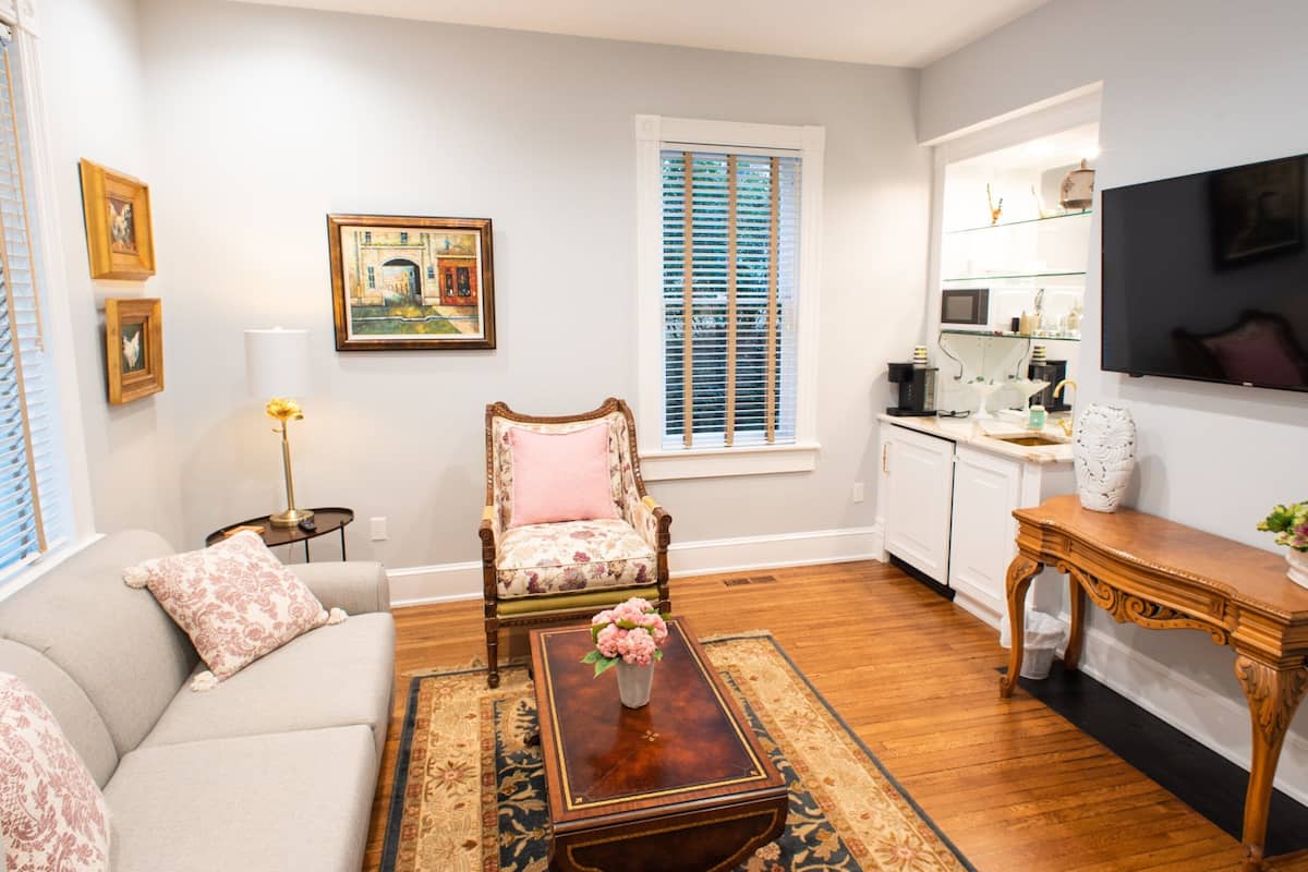 A living room with a sofa, armchair, coffee table, and a painting on the wall.