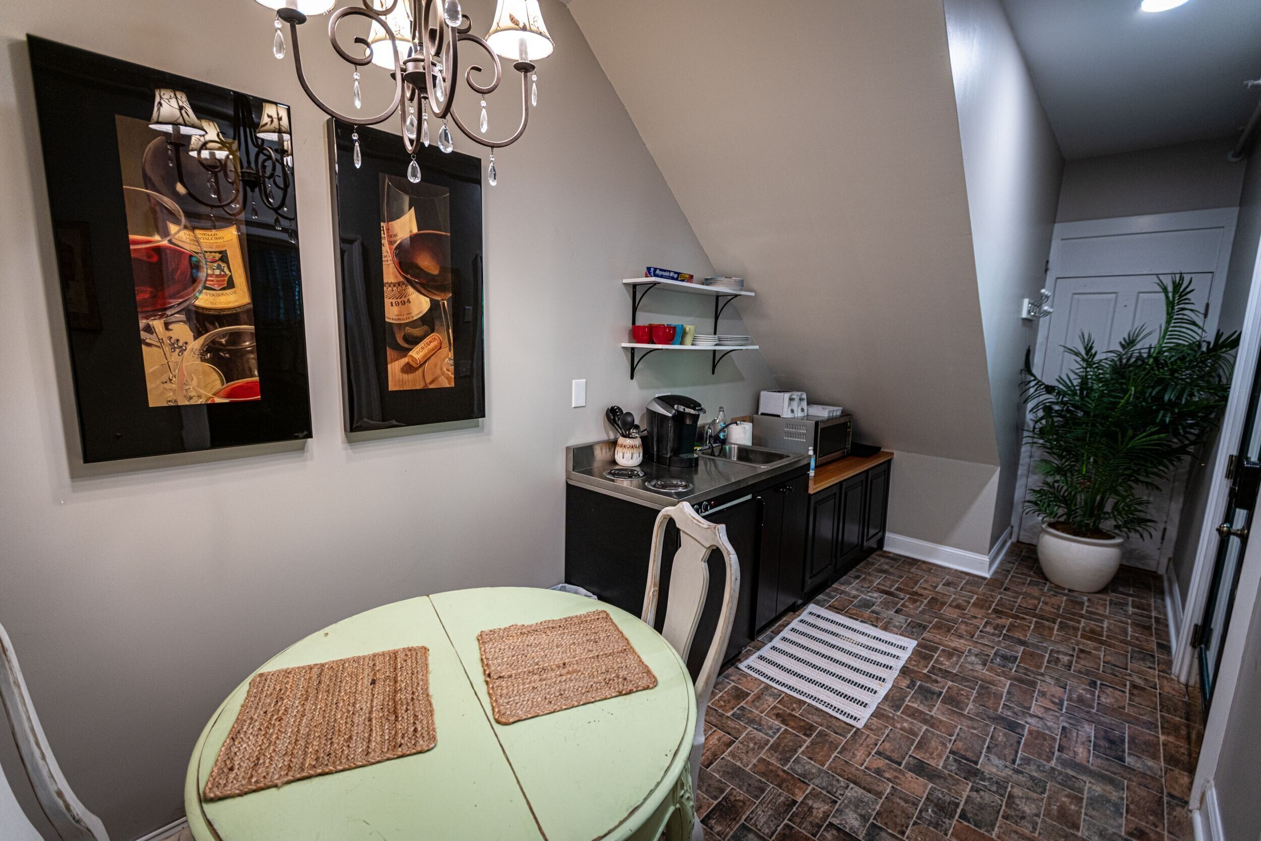 A compact kitchen with a dining table, a chandelier, and a potted plant.