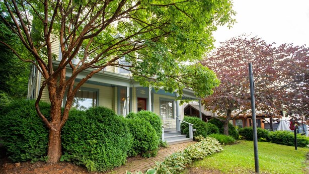 A two-story house with a covered porch, a brick pathway, and well-maintained hedges. - Washington Street Quarters (Lewisburg)