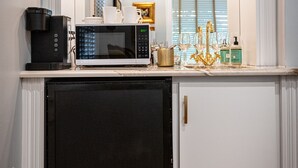 A compact kitchen with a microwave, coffee maker, and wine glasses on the counter. - Washington Street Quarters (Lewisburg)