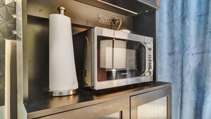 Una cocina con un microondas sobre la encimera, un rollo de toallas de papel y un enchufe.