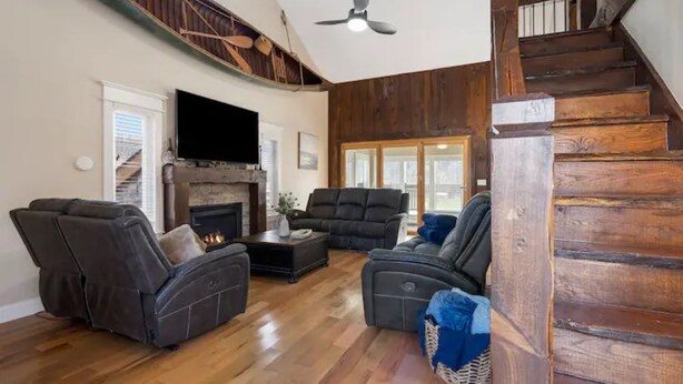 Amplia sala de estar con chimenea, pisos de madera y una escalera.