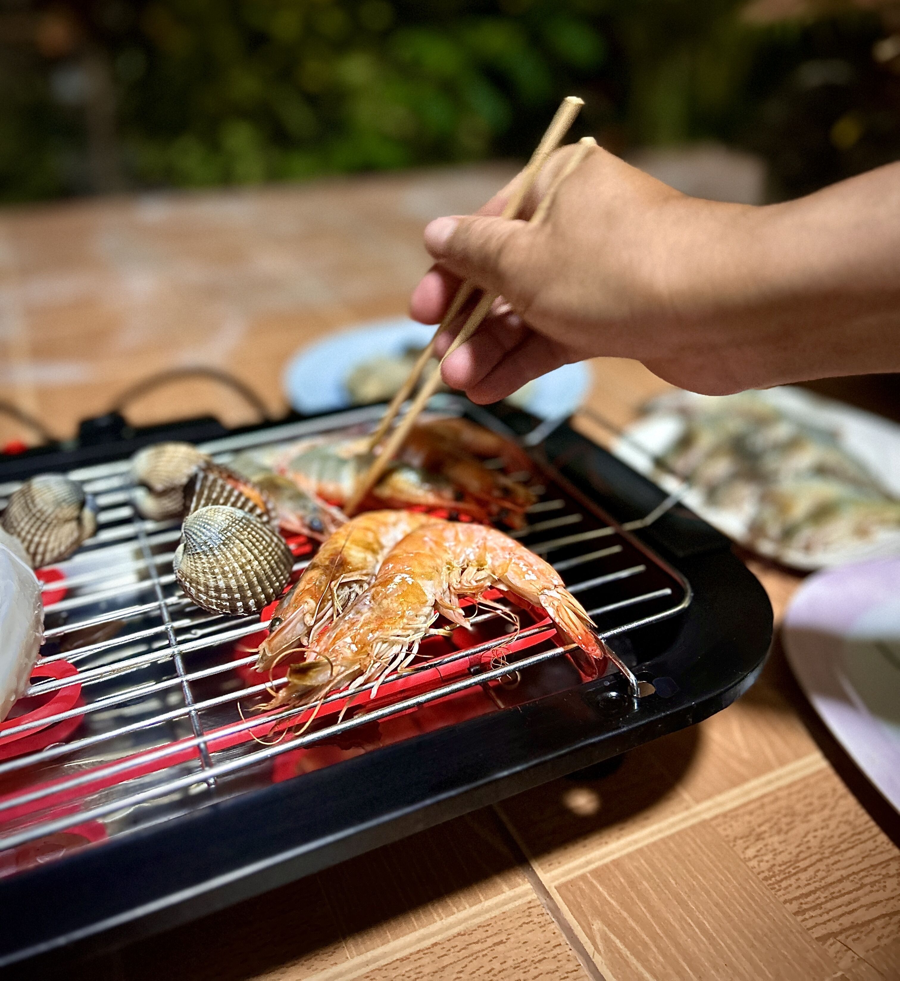 A person grilling seafood on a portable grill.