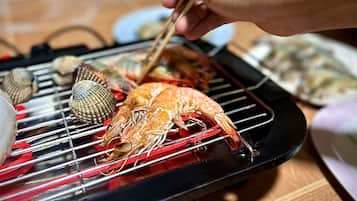 A person grilling seafood on a portable grill.
