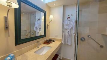 Un baño moderno con un espejo grande, un lavamanos y una cabina de ducha de vidrio.