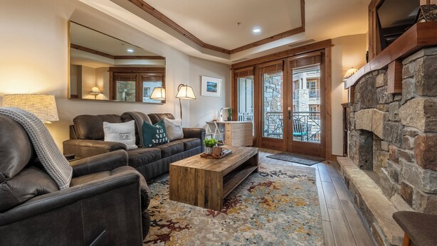 A cozy living room with a stone fireplace, leather sofas, a wooden coffee table, and a large mirror. - Premier 1 BD/1 BR condo ski in and out.  Gondola is right outside the condo. (Truckee)