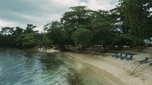 A beach with clear water, trees, and blue lounge chairs. - Negril Bungalow Paradise overlooking cliffs with Private Snorkeling Entrance. (Hanover Parish)
